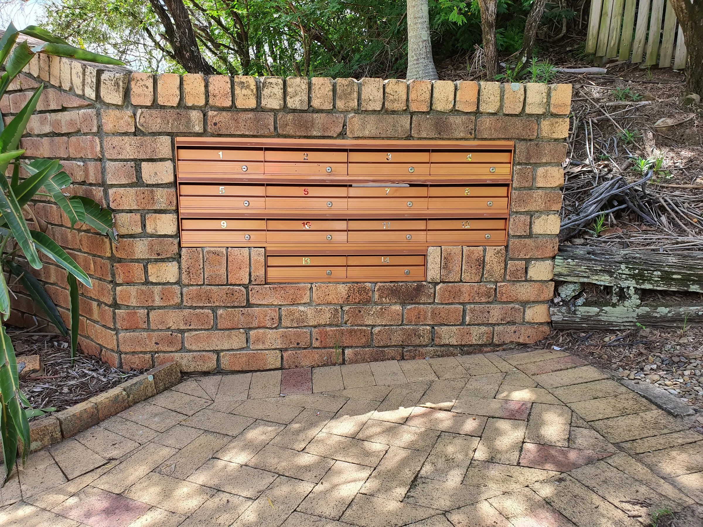 A new hardwood letterbox bank set into the brick wall of a unit block, numbered and keyed.