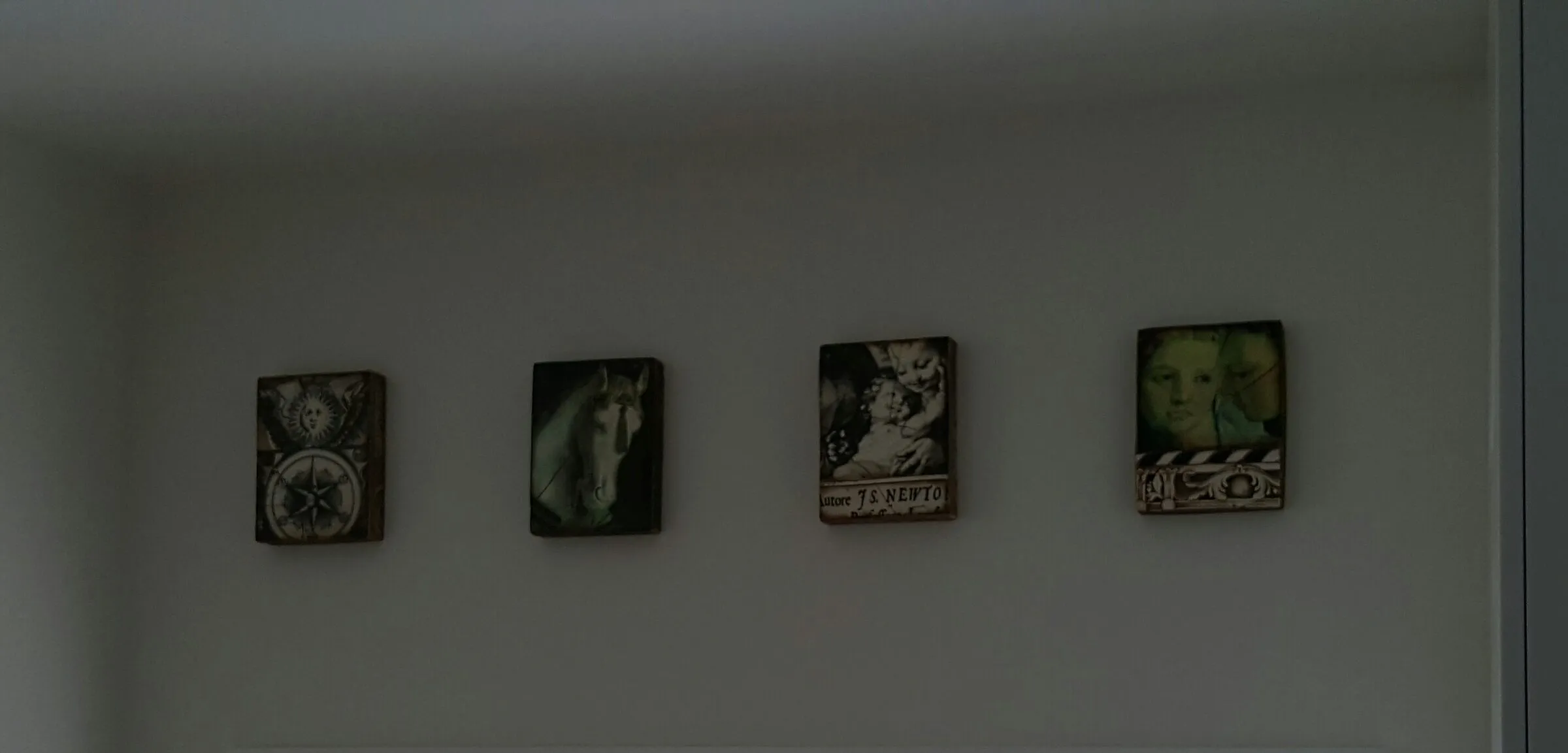 Four small framed pieces hung to a line along a wall.