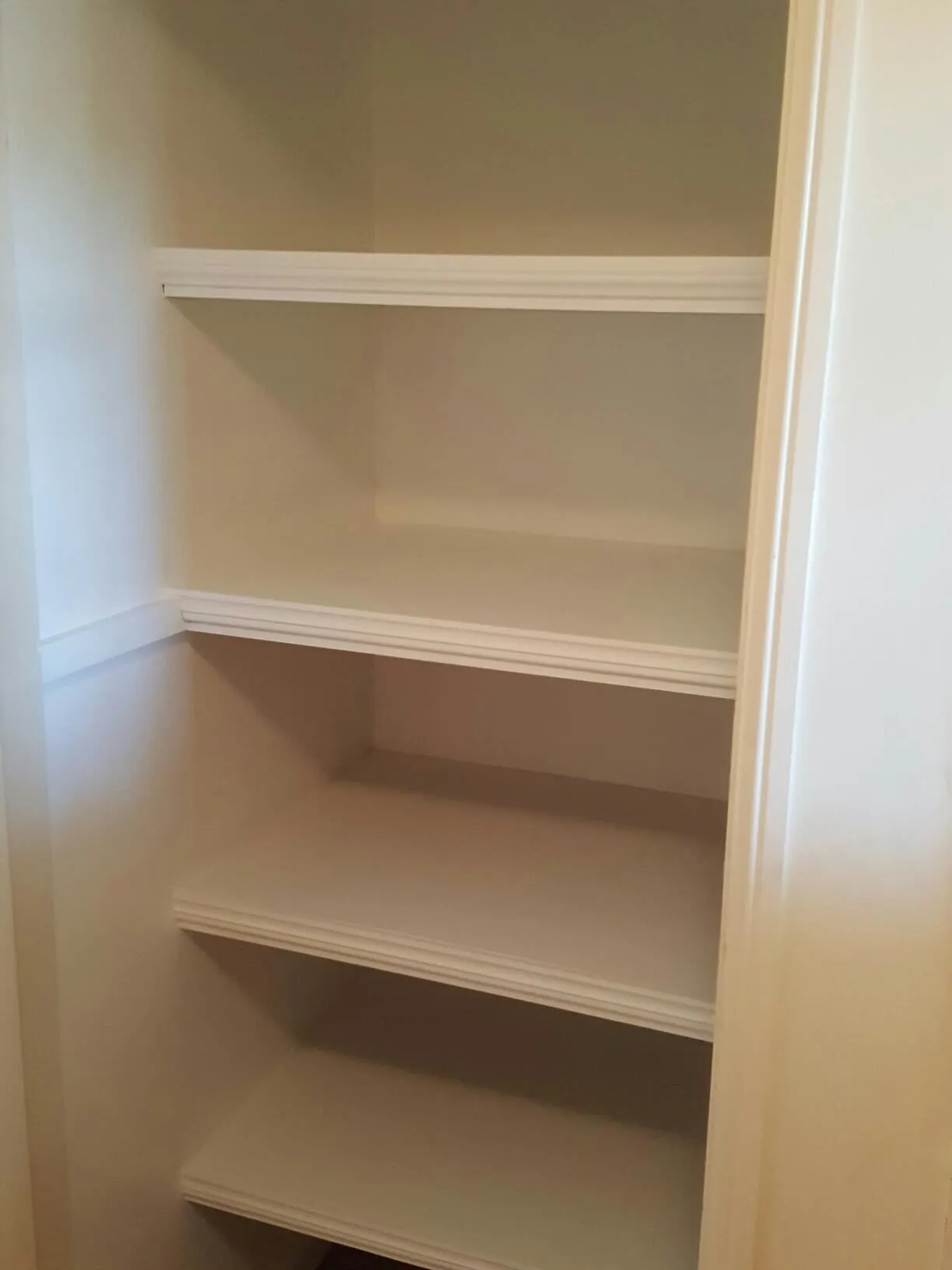 White-painted built-in shelving fitted into a recess, four fixed shelves.