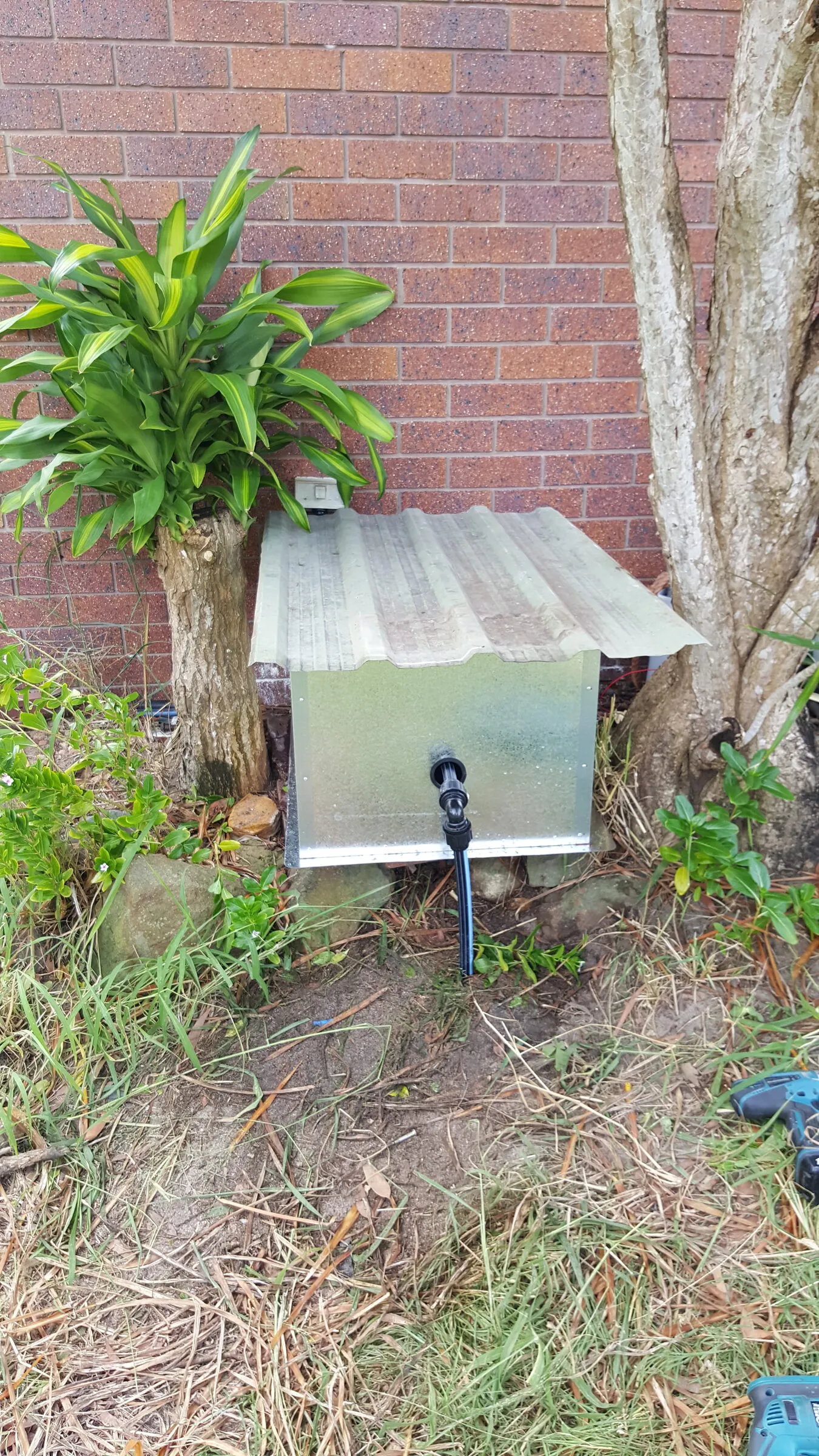 A folded galvanised cover made to fit over an outdoor valve set, with a sloped lid to shed water.