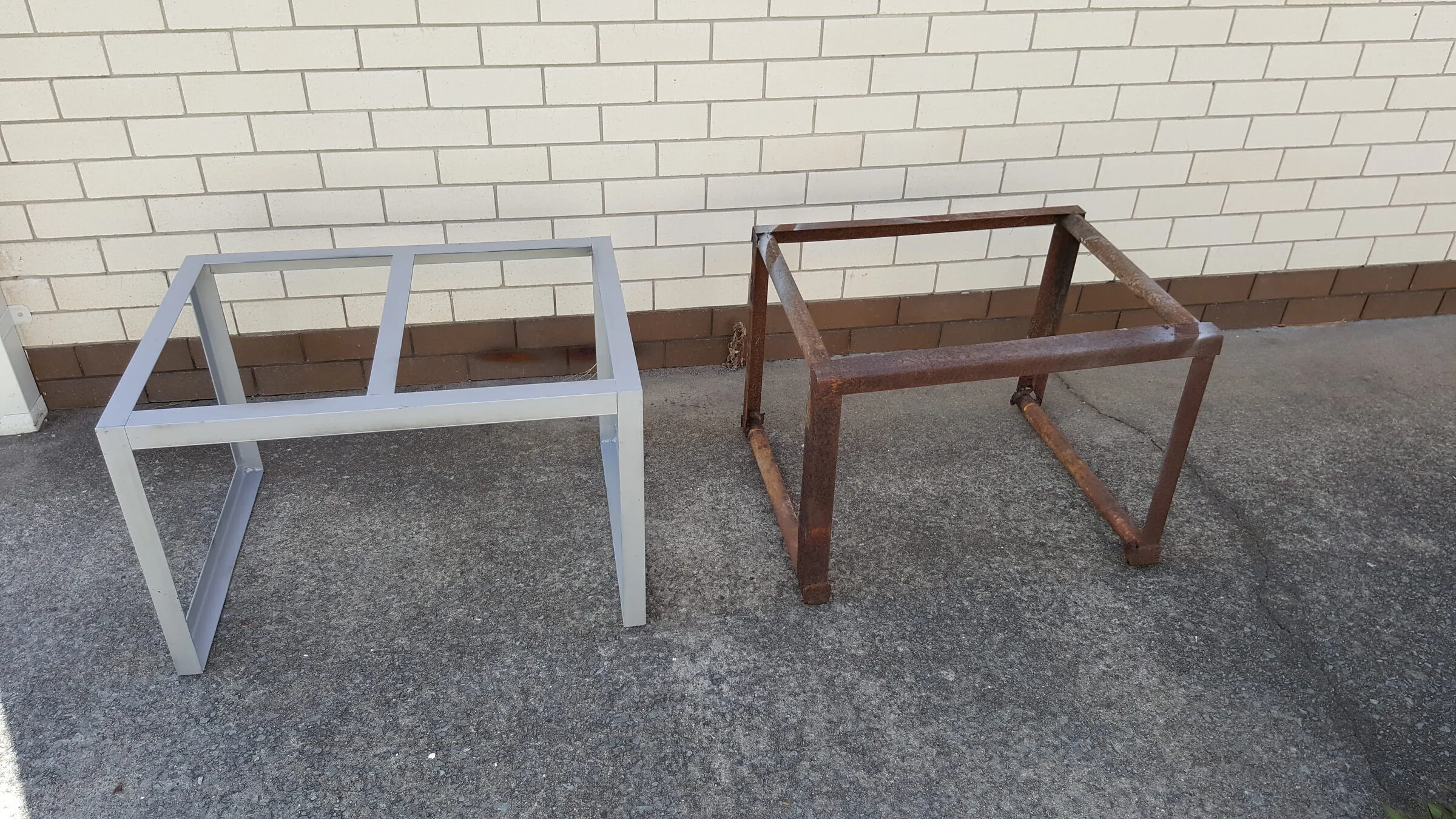 Two custom-welded steel frame stands, one in galvanised finish and one in bare steel.
