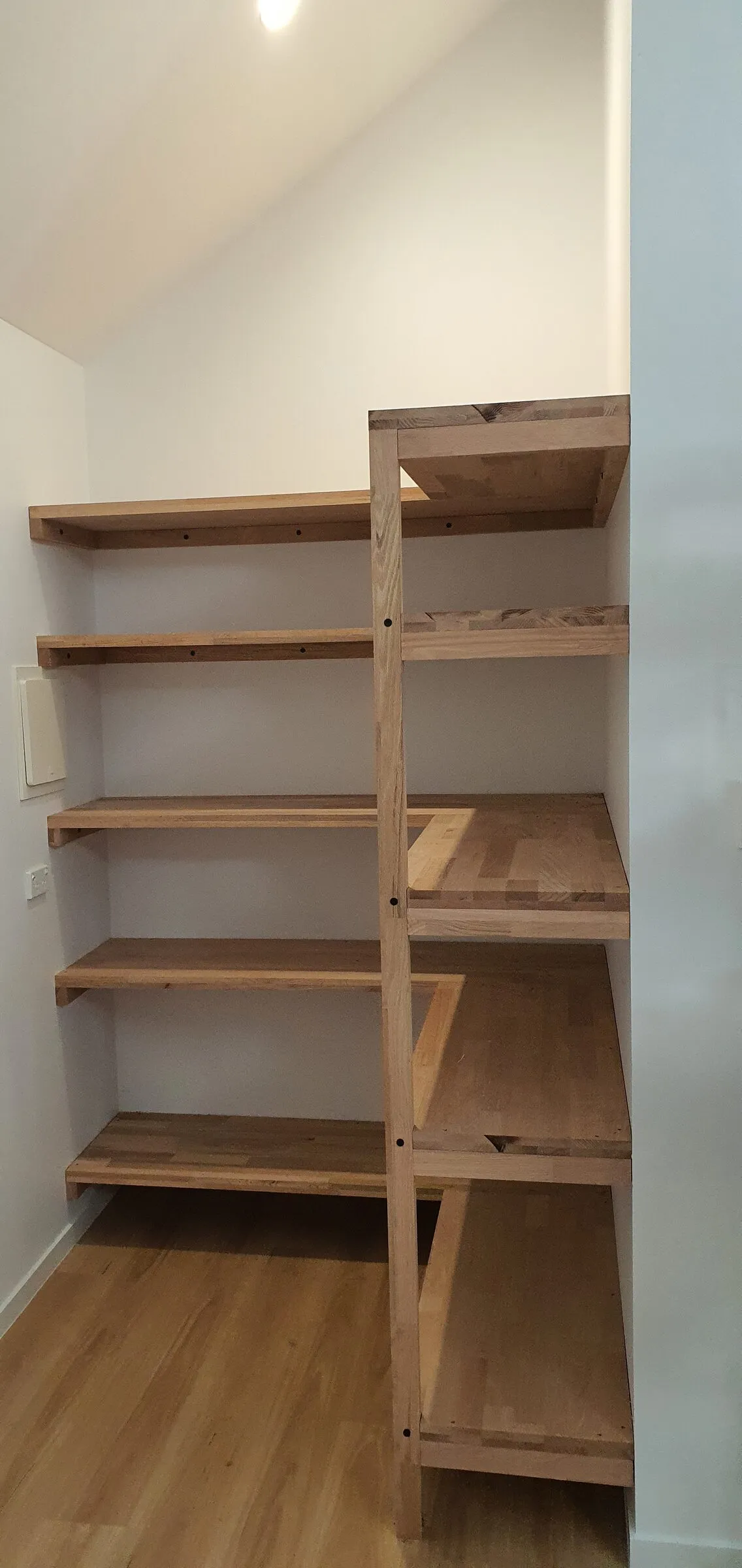The finished pantry shelving from the doorway, timber shelves stepping around the corner.