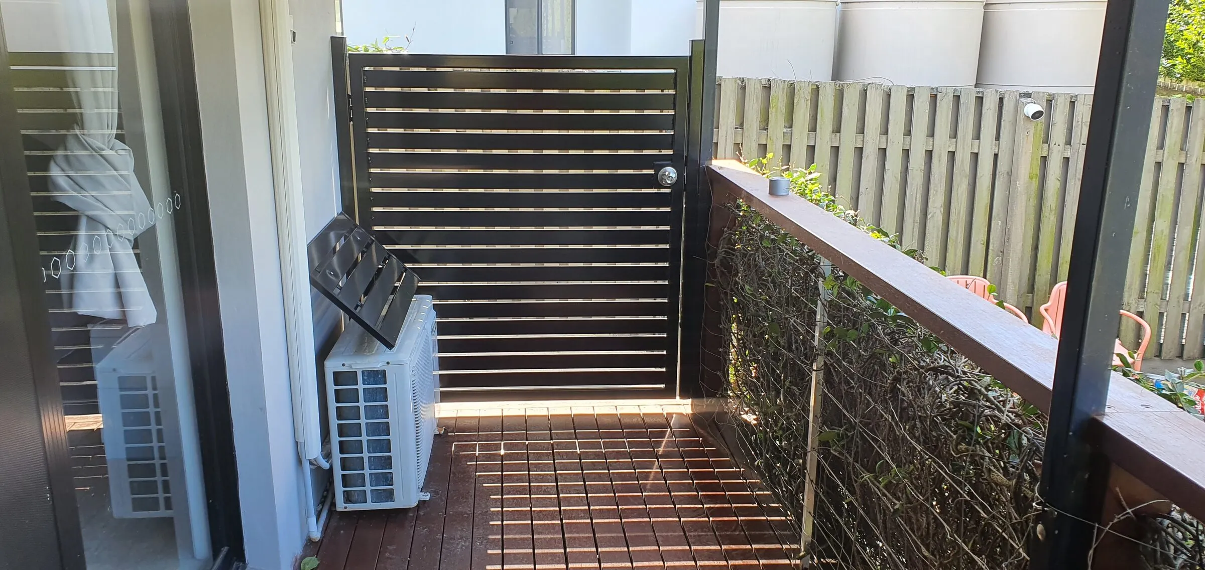 Aluminium slat gate and matching balustrade off a timber deck landing.