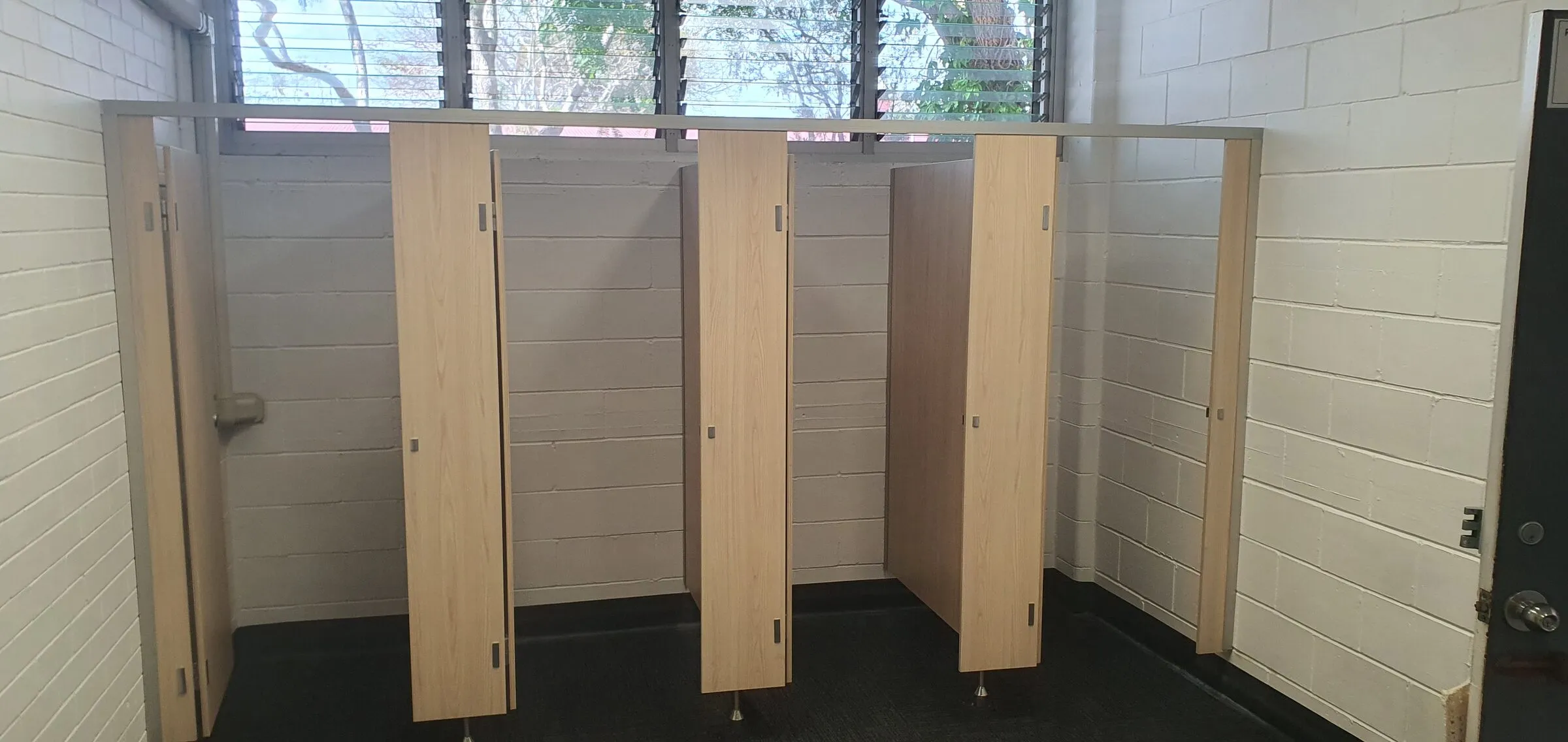 The same change-room cubicles seen from the front, partitions standing true between the block walls.