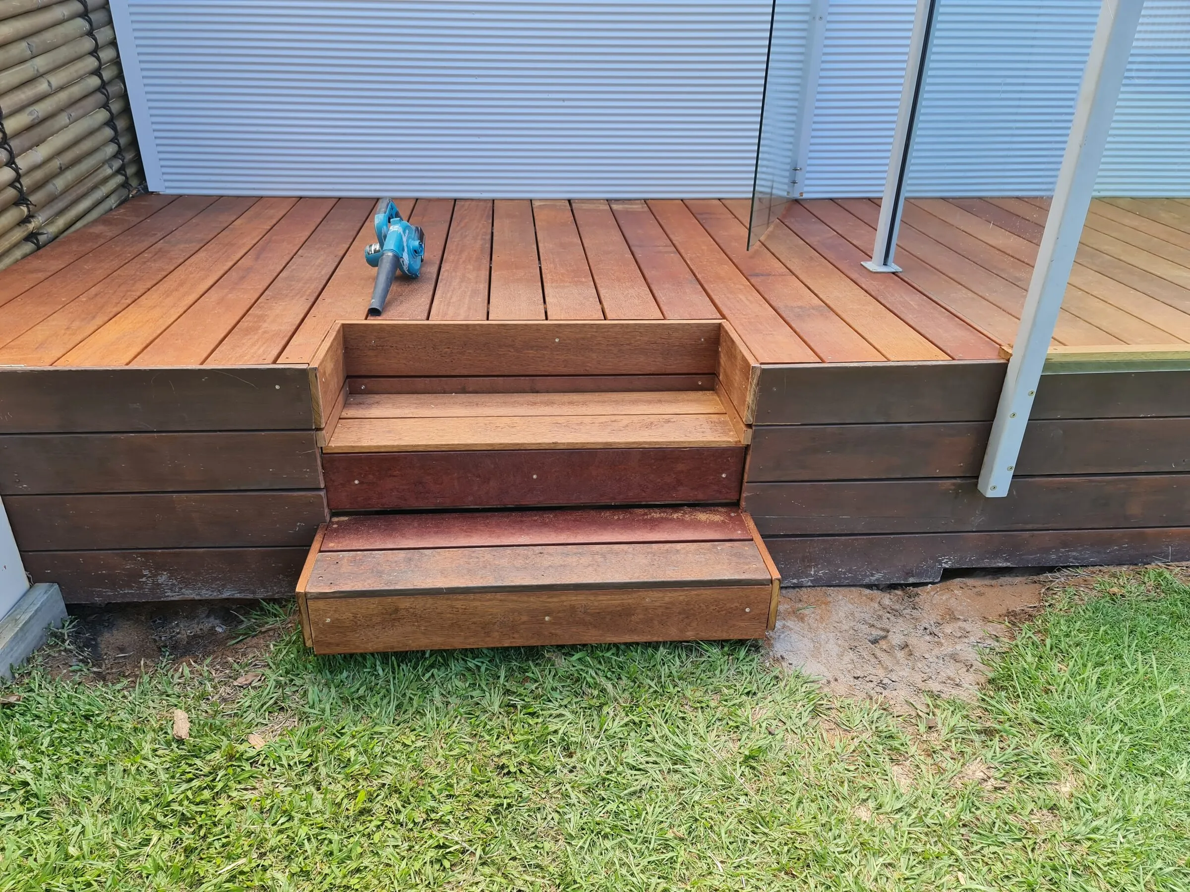 New hardwood steps down from the deck to the lawn, treads and risers in matching boards.