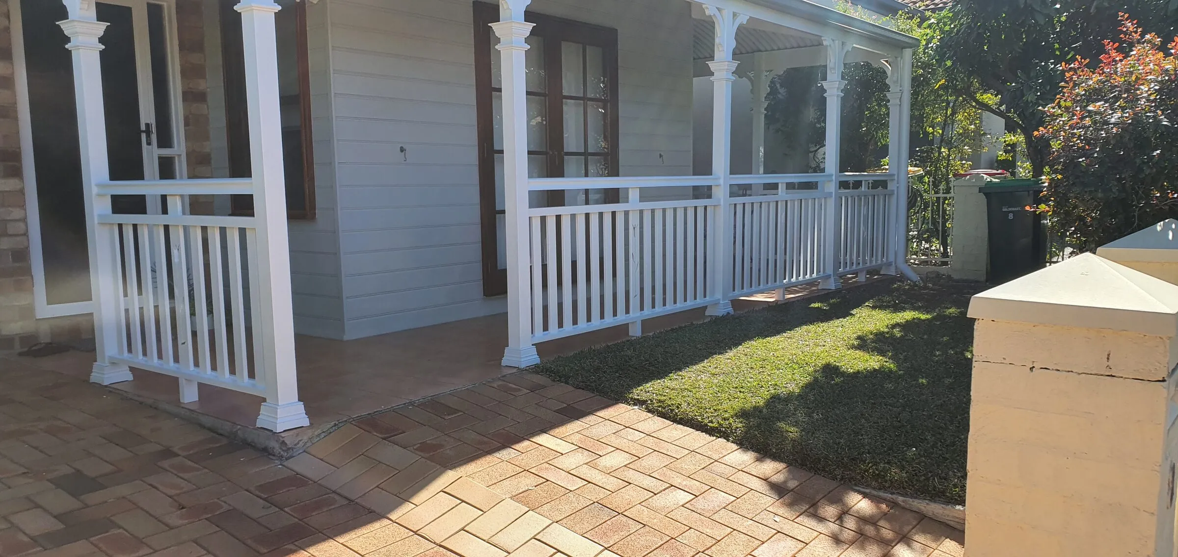 The finished balustrade and posts along the front of the cottage, seen from the paved path.