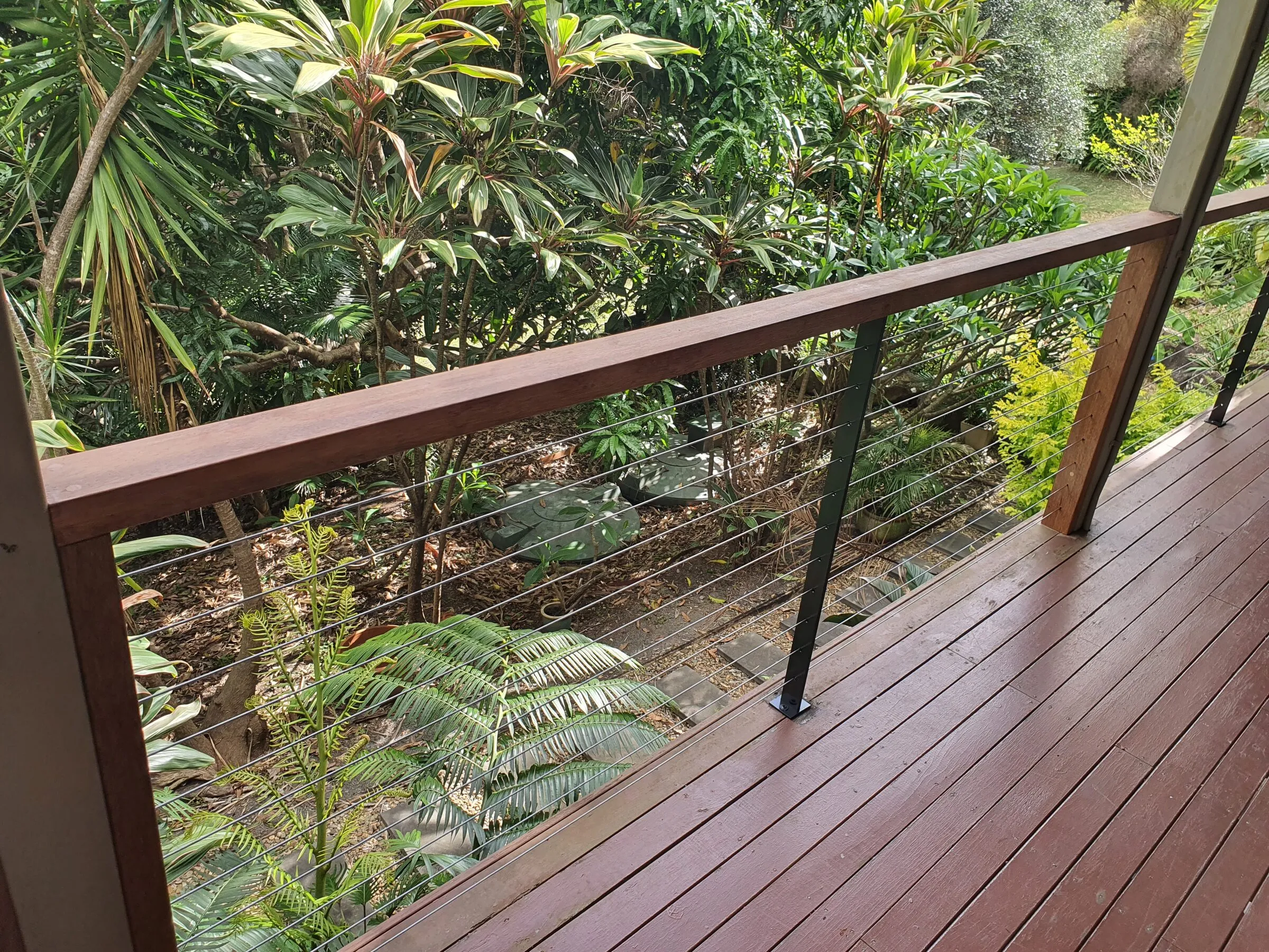Wire balustrade and hardwood top rail close up, oiled boards running away into the corner.