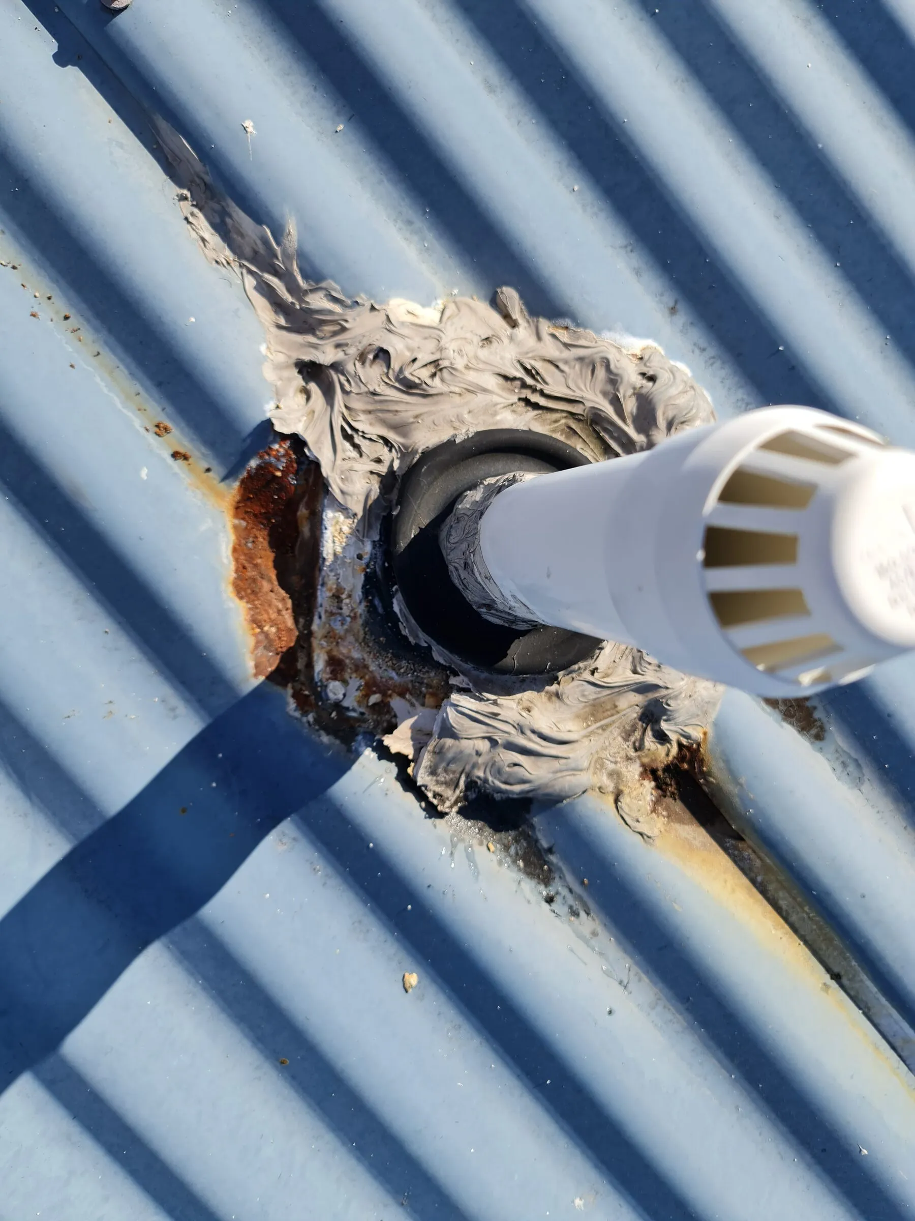 A perished pipe flashing boot, ringed with cracked sealant and rust where water had been getting in.