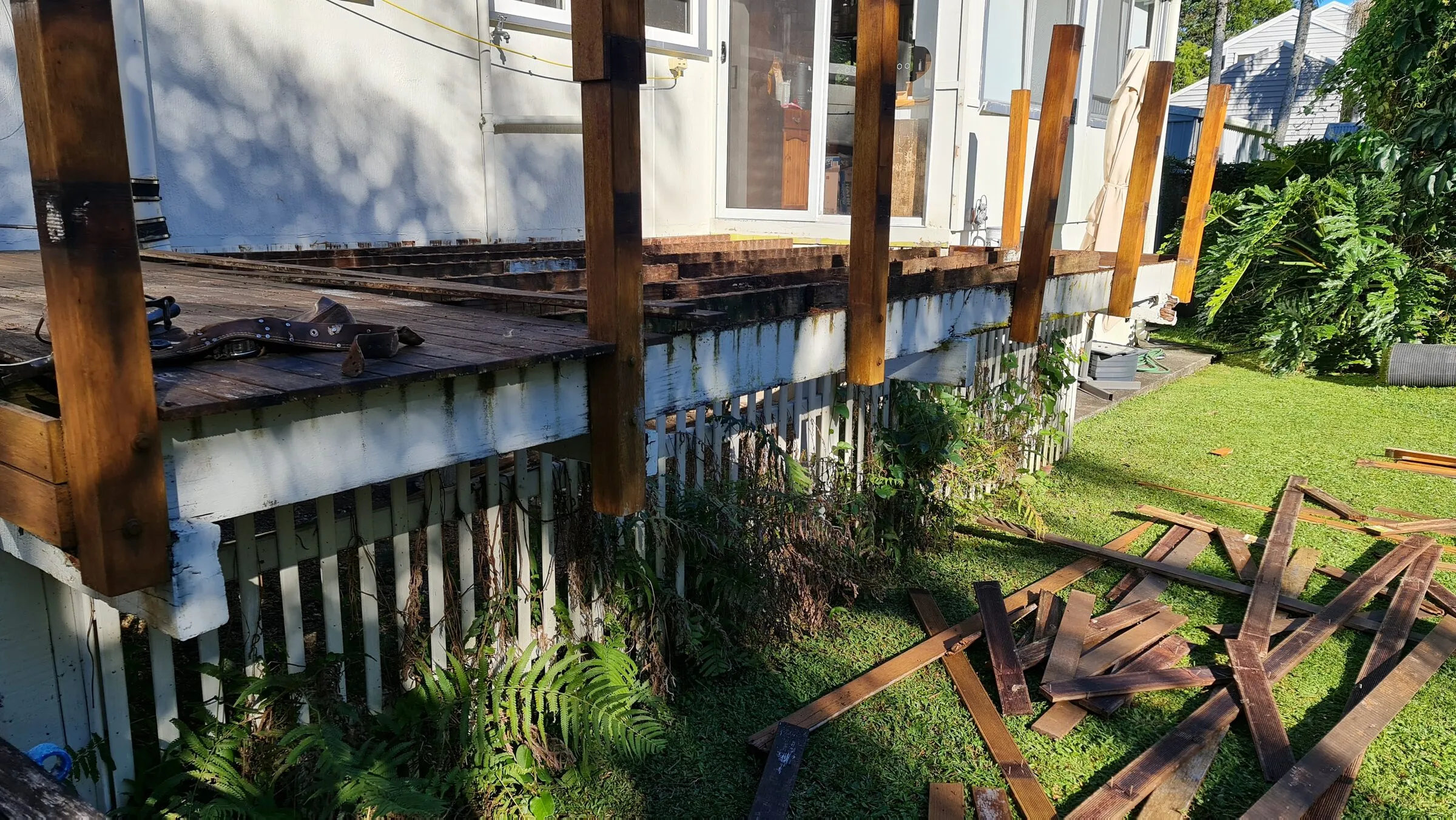 The old deck stripped out, the salvaged boards stacked across the lawn.