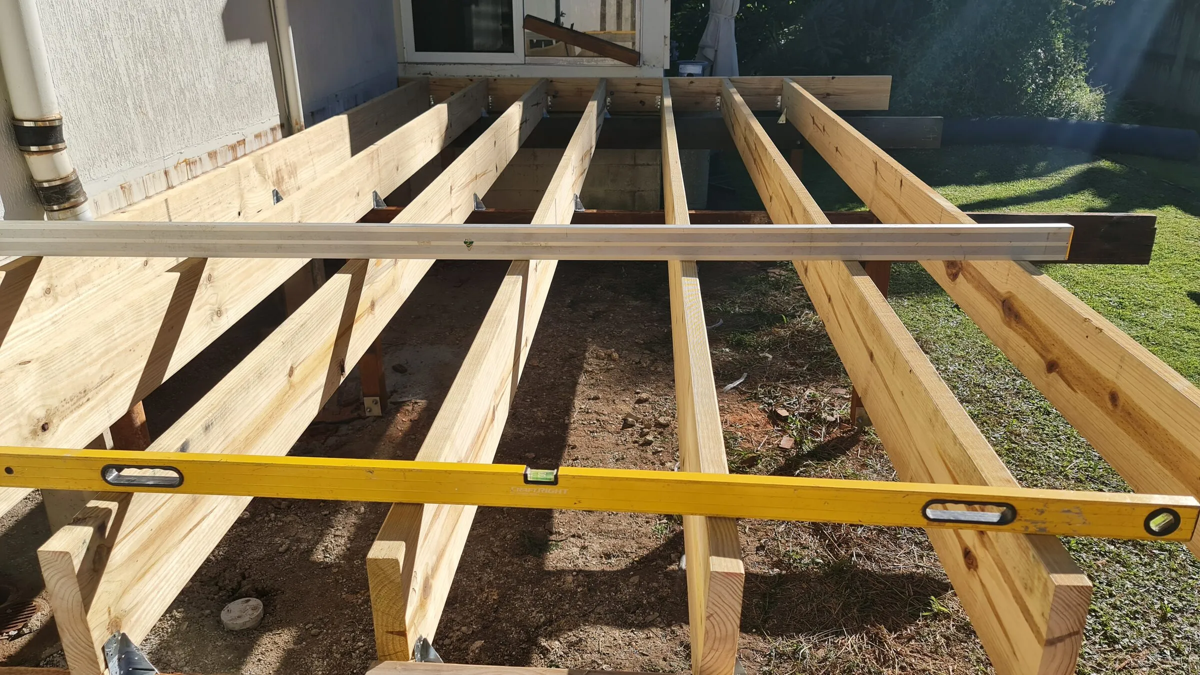 New treated bearers and joists set out and levelled off the house wall.